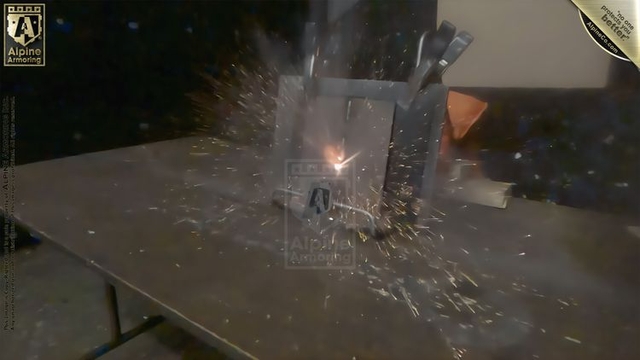 A close-up view of a steel plate being tested, with sparks flying upon impact, demonstrating the material's durability and resistance. The test is conducted in an indoor setting, with the steel plate positioned on a table.