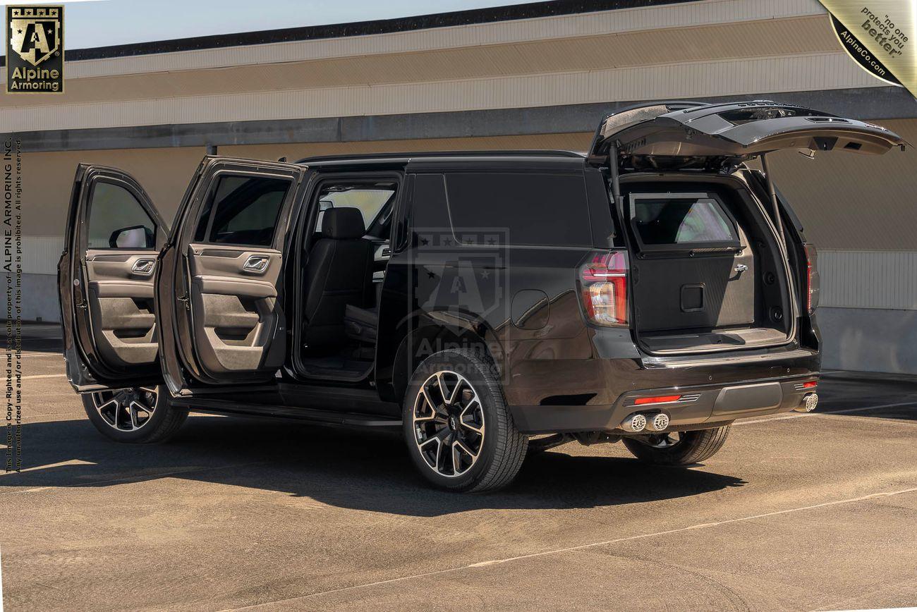 A black bulletproof Chevrolet Suburban LT SUV with all doors and the trunk open, showcasing the vehicle's interior and cargo space. The vehicle is parked in an outdoor lot.