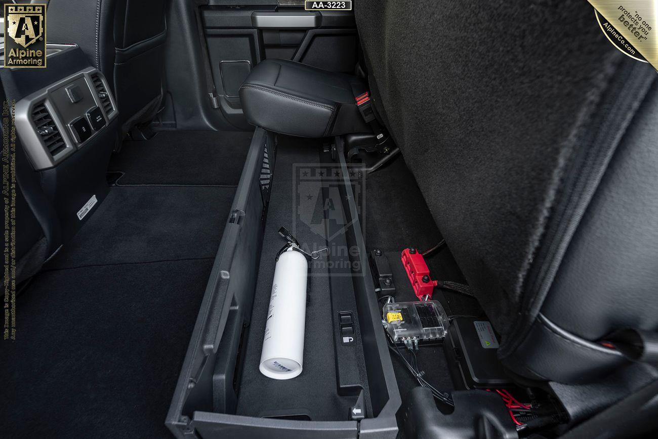 Interior view of a Mastiff, showcasing an under-seat storage compartment holding a fire extinguisher, a small battery, and an electrical device.