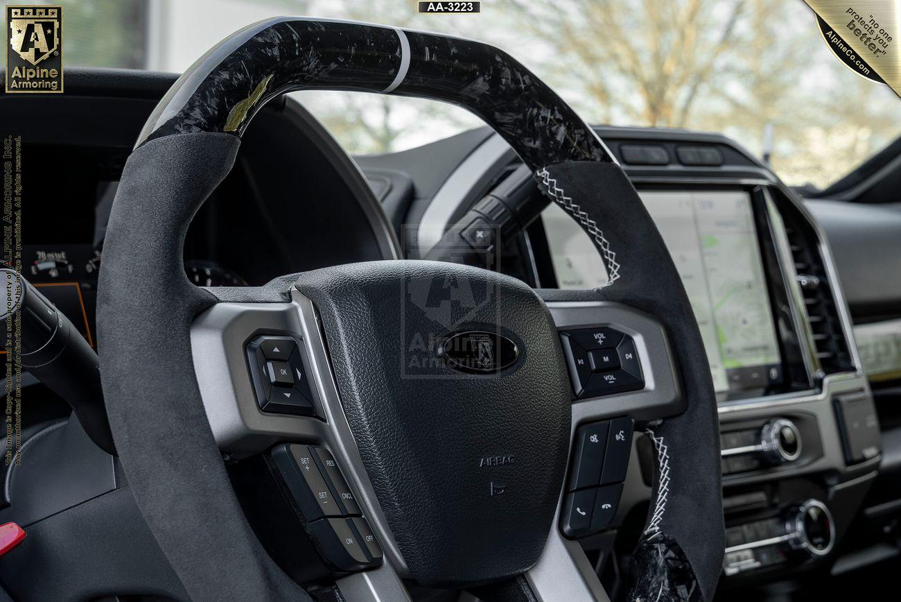 Close-up view of a Mastiff's steering wheel and dashboard. The dashboard display shows navigation instructions, and various controls are visible on the steering wheel and center console.