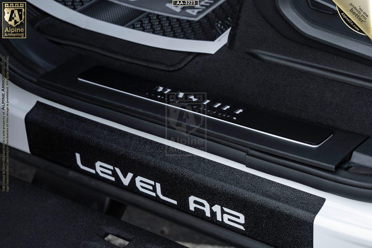 Close-up of a Mastiff door sill with "LEVEL A12" and "VITAL ARMOR" branding, showing part of the car's interior and door frame.