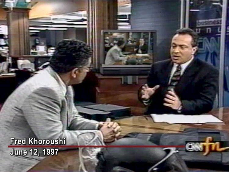 Two men having a conversation on a TV news set, one dressed in a suit speaking, and the other listening. Text on screen reads: "Fred Khoroushi June 12, 1997.