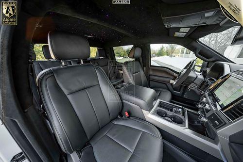 Interior of a Mastiff with black leather seats, a touchscreen dashboard, and a panoramic sunroof. The view shows the front and part of the rear seating area.