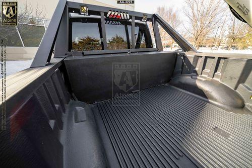 The image shows the bed of a Mastiff truck with a reinforced roll bar and rubberized bed liner. The truck appears to be outdoors near a building and trees.