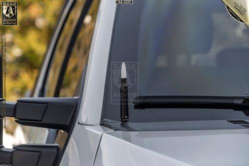 A close-up of a white Mastiff with a black bullet-shaped antenna on top of the windshield wiper pivot. The antenna's design contrasts with the vehicle's traditional elements.