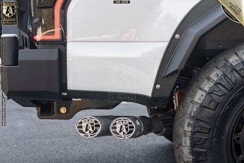 Close-up of a Mastiff's rear, showing dual exhaust pipes with custom Alpine Armoring branding and a robust off-road tire.